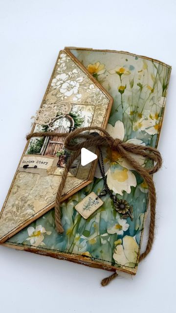 an altered book with flowers and tags on the front, tied up to it's cover