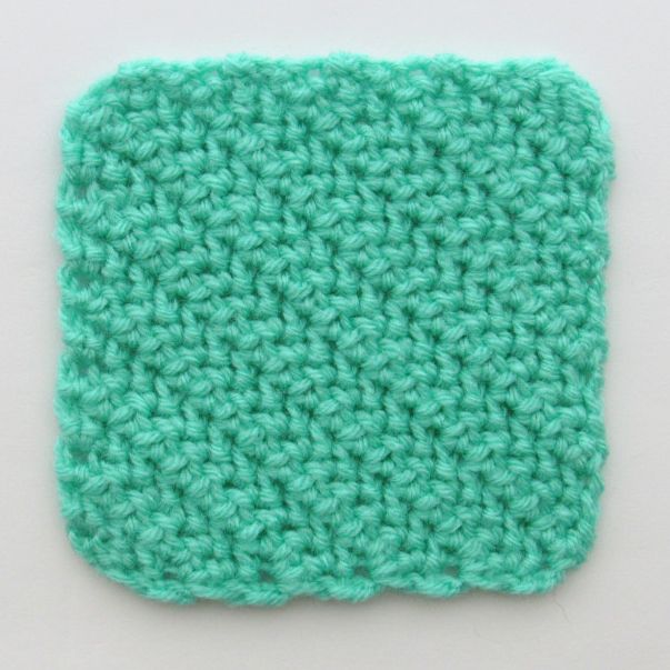 a crocheted square is shown on a white surface, with the corner stitched in