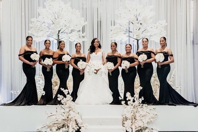 a group of women standing next to each other in front of a white backdrop with flowers