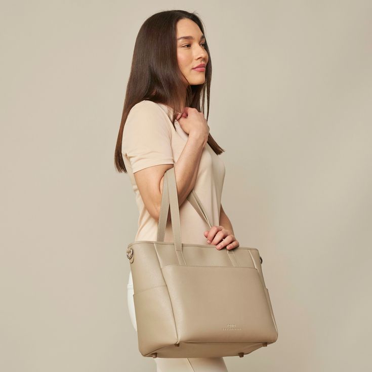 This structured tote is the ultimate do-it-all bag that you deserve. It's the perfect carryall for work, travel, and anywhere your day brings you. It features a spacious and organized interior for your essentials, a padded compartment for your laptop, side pockets for your drinks, and you can convert it into a backpack or crossbody. Crafted from premium American Saffiano leather that's waterproof and scratch-resistant, the Transform Tote will stay just as beautiful through all your travels and a Modern Weekender Bag With Removable Pouch For On-the-go, On-the-go Tote Bag With Laptop Sleeve, Chic Tote Laptop Bag For On-the-go, Trendy On-the-go Tote Laptop Bag, Chic Rectangular Laptop Bag For On-the-go, Chic Double Handle Satchel With Luggage Sleeve, Chic Large Capacity Weekender Bag For On-the-go, Trendy Tote Laptop Bag For Travel, Chic Beige Weekender Bag For On-the-go