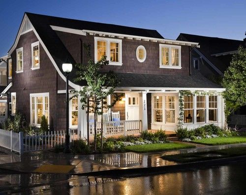 a large house with lots of windows and lights on it's front porch at night