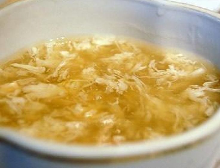 a white bowl filled with soup sitting on top of a table next to plates and utensils