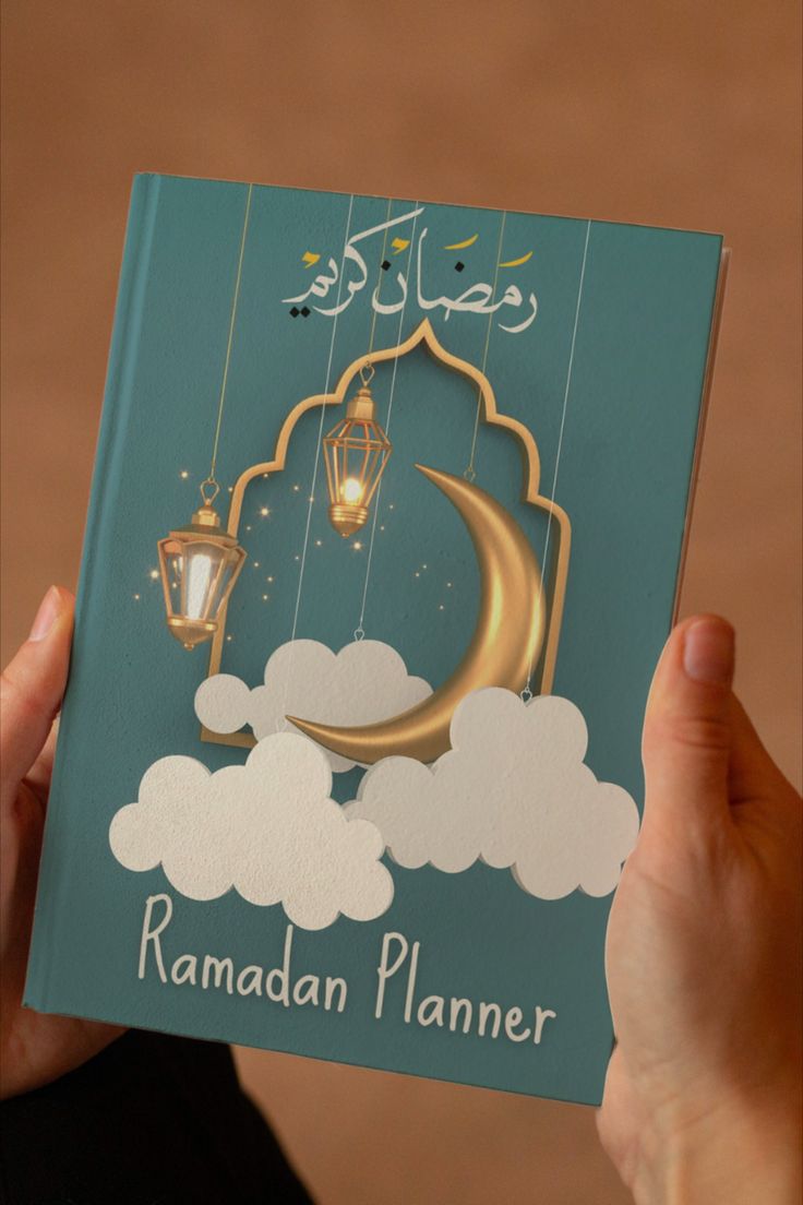 a person holding up a rama planner in front of a brown background with clouds and a lantern