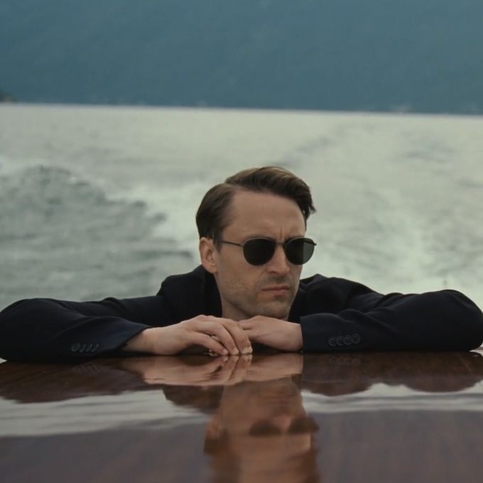 a man wearing sunglasses sitting at the edge of a boat