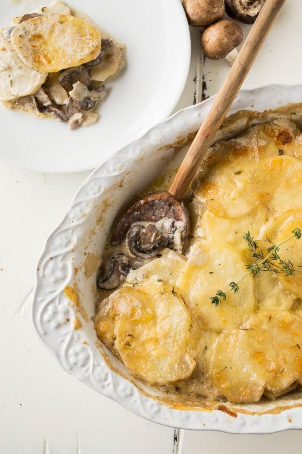 a casserole dish with mushrooms and cheese in it on a white table top