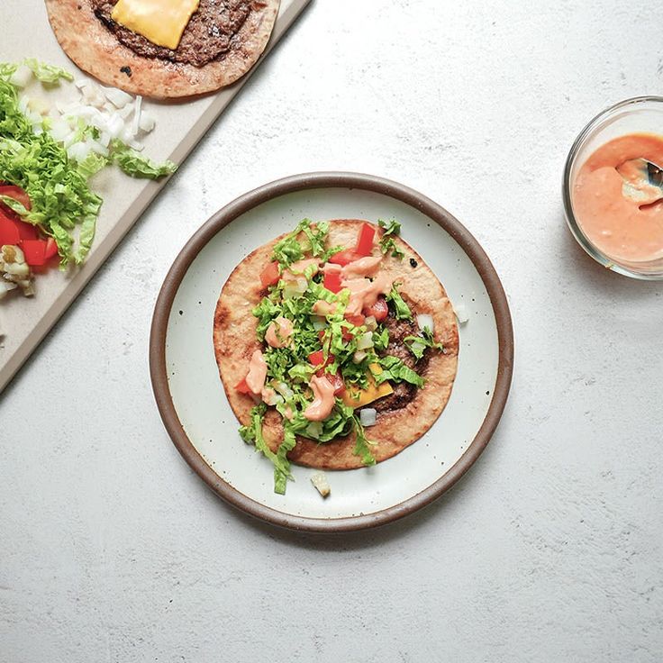 three tacos are on a plate with limes and other food items around it