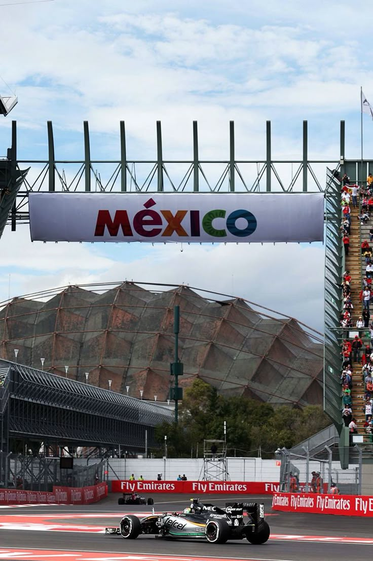 a race car driving down a track under a sign that says mexico on it's side