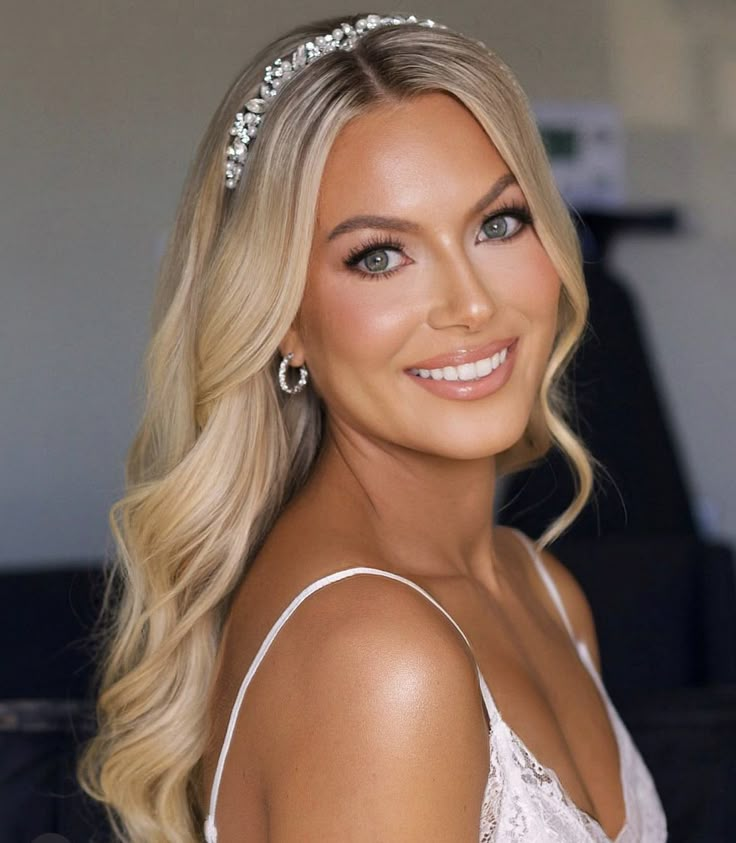 a woman with blonde hair wearing a tiara and smiling at the camera while standing in front of a couch