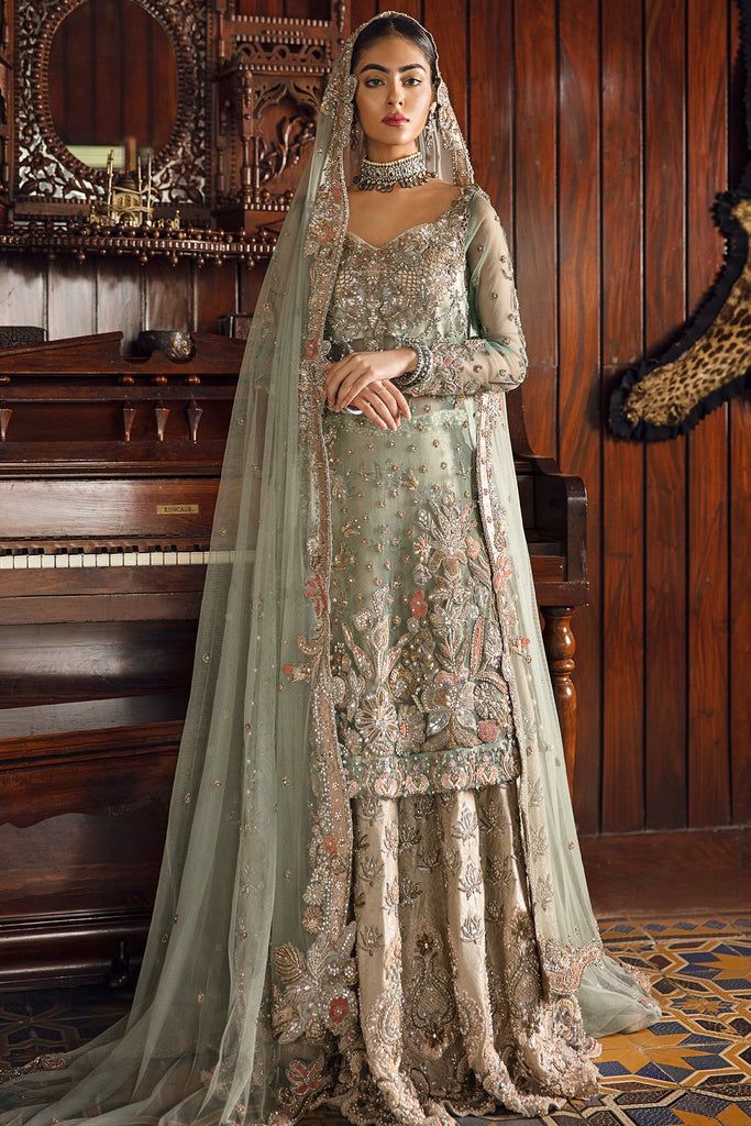 a woman standing in front of a piano wearing a long dress with an elaborate veil