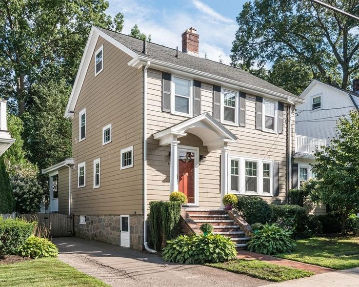 a two story house with white trim and red door