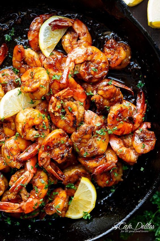 cooked shrimp with lemon and parsley in a cast iron skillet, ready to be eaten