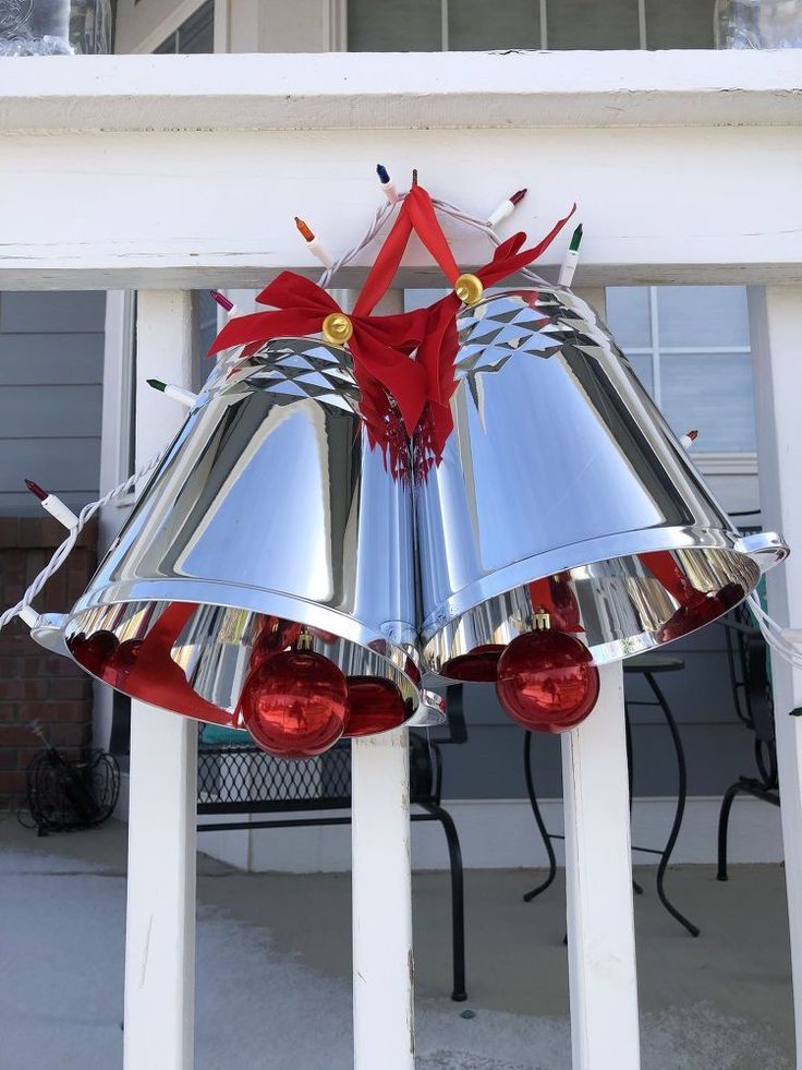 two bells with red bows on them are attached to the side of a white house