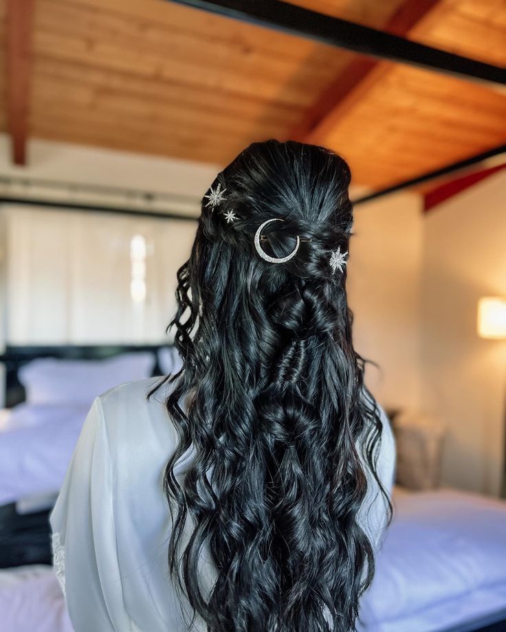 the back of a woman's head with long curly hair and silver rings on it