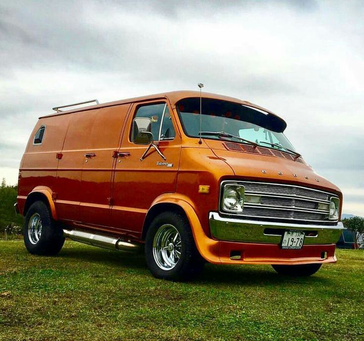 an orange van parked on top of a lush green field