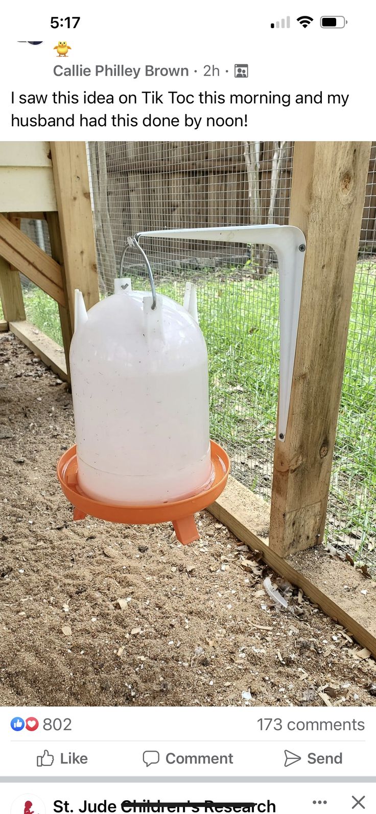 an orange and white container sitting on top of a dirt ground next to a wooden fence