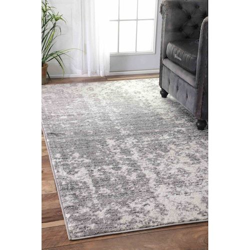 a gray and white rug with a chair in the background