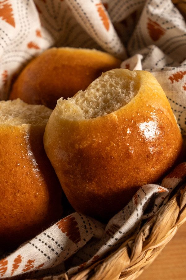 three muffins sitting in a basket on top of a wooden table next to a white and orange cloth