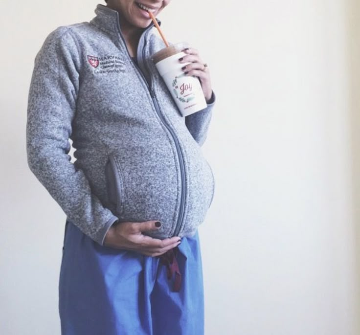 a pregnant woman holding a coffee cup in her right hand