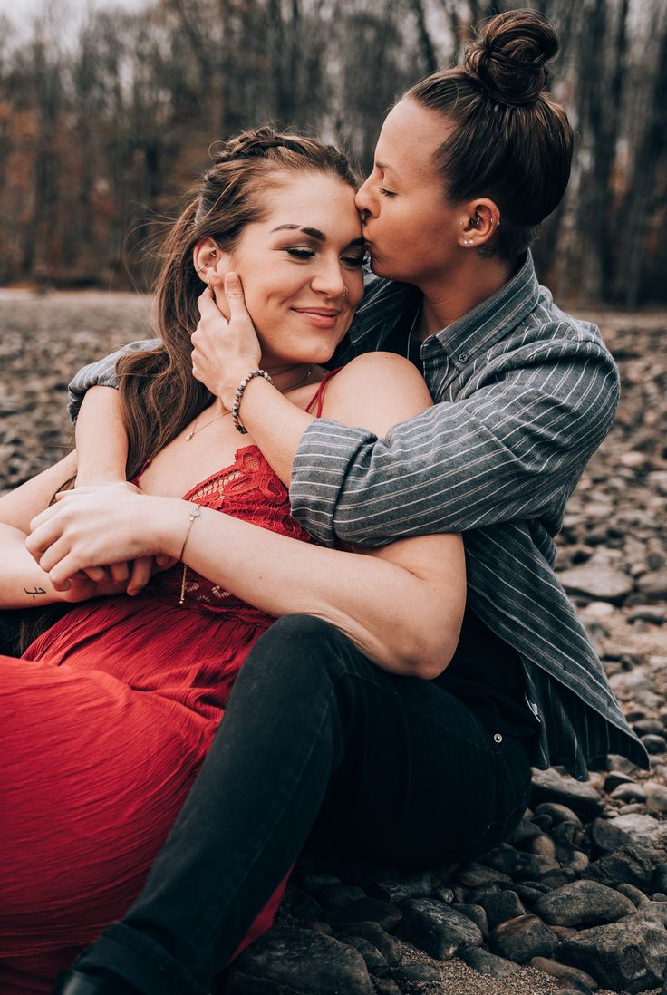 two women are sitting on the rocks and kissing