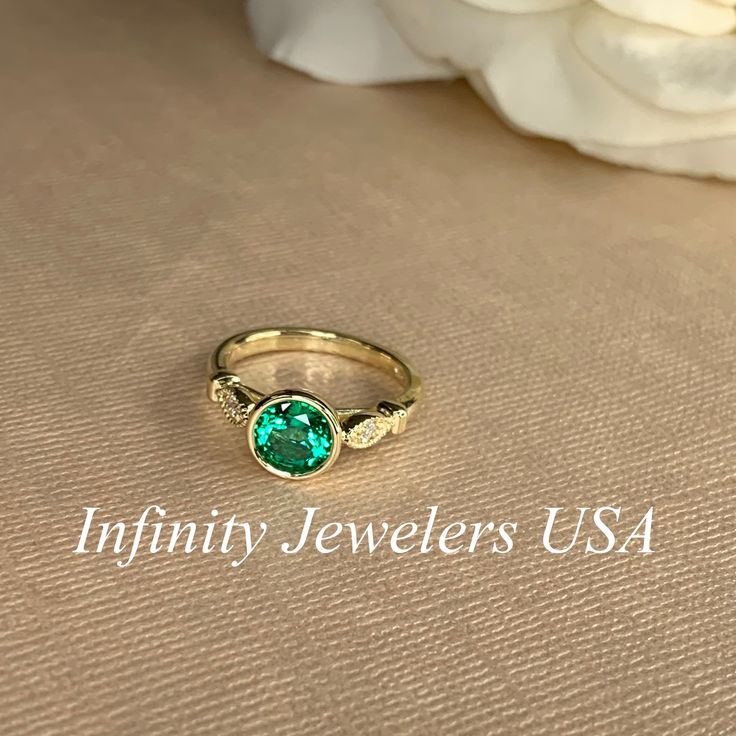 "The ring pictured is lab created emerald with moissanite accents #7056 -Approximate total carat weight: 1.26ctw diamond equivalent -Center Stone Size: 7mm - approx. 1.20ct diamond equivalent -Center Stone Shape: round -Gem Type: lab created emerald -Stone Clarity: VS2 -Stone Color: green -Moh's Scale: 8.5 hardness -Accent Stones: 2 rounds - approx. 0.06ctw. diamond equivalent -Gem Type: moissanite -Stone Clarity: VS2 -Stone Color: FG -Moh's Scale: 9.25 hardness -Metal Type and Purity: 14k white Emerald Bezel Setting Birthstone Ring For May, Emerald Birthstone Ring With Bezel Setting For May, Green Diamond Birthstone Ring With Accent Stones, Green 14k Gold Birthstone Ring With Accent Stones, Emerald Bezel Setting Promise Ring For May Birthstone, Emerald Ring With Diamond Center Stone For May Birthstone, Emerald Diamond Ring For May Birthstone With Center Stone, Emerald Birthstone Ring With Bezel Setting, May Birthstone Emerald Ring With Diamond Center Stone