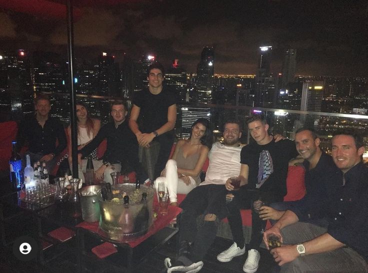 a group of people sitting on top of a red couch in front of a city skyline