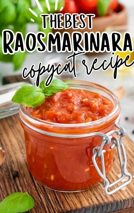 a jar filled with marinara sauce on top of a wooden cutting board next to basil leaves