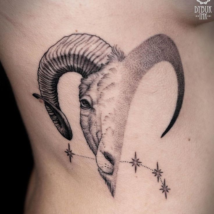 a ram tattoo on the side of a woman's stomach with stars around it