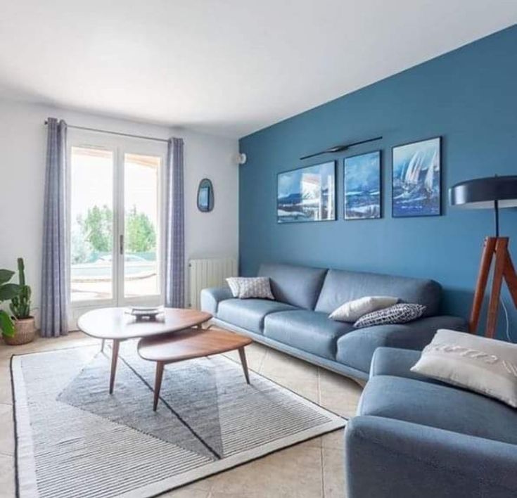 a living room with blue walls and white carpeting, two couches and a coffee table