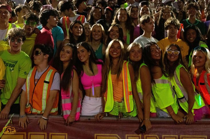 a group of young people standing next to each other in front of a large crowd