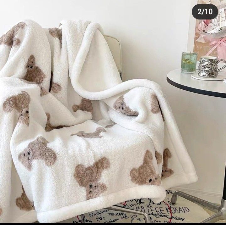 a teddy bear blanket sitting on top of a chair next to a table with a cup