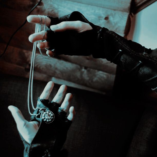 a woman wearing black gloves and holding onto a chain with her hands on the couch