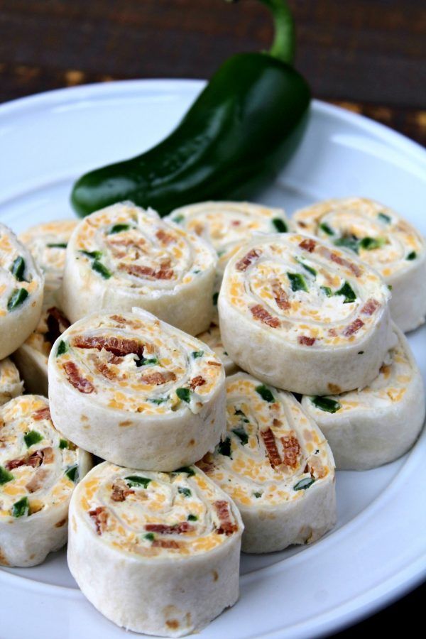 a white plate topped with rolls covered in cheese and green peppers next to a hot pepper