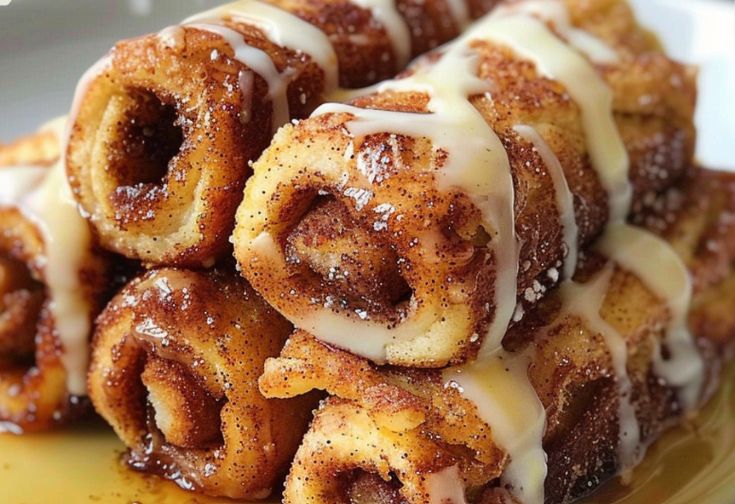 a pile of cinnamon rolls sitting on top of a yellow plate covered in icing