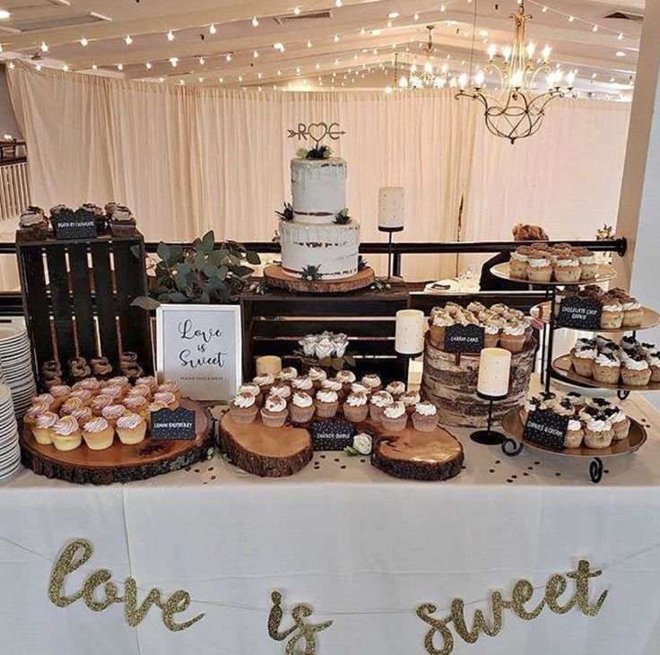 a table topped with cakes and cupcakes next to a sign that says love is sweet