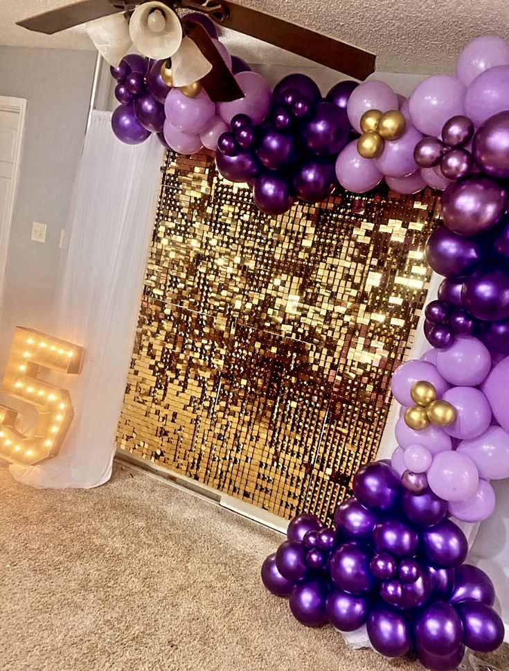 the balloon arch is decorated with purple and gold balloons