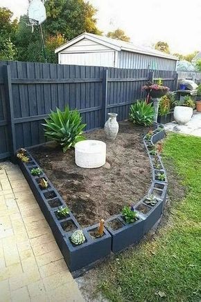 a garden with various plants in the middle of it, and a fence behind it