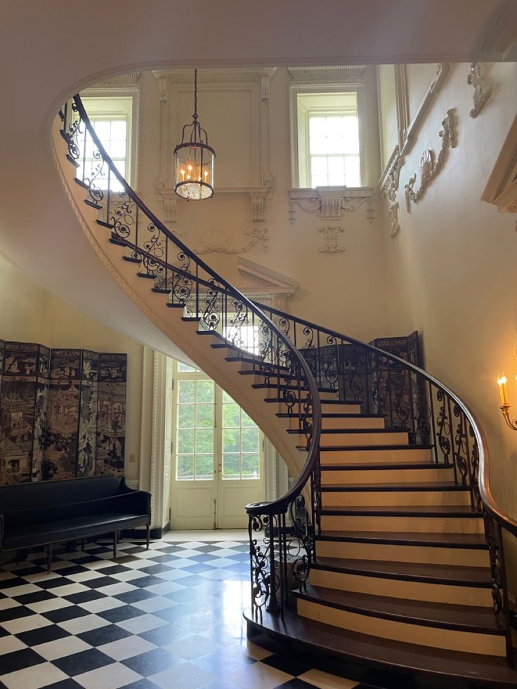 an elegant staircase with wrought iron railing and chandelier