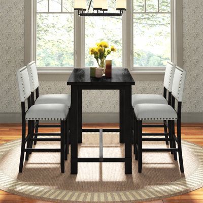 a dining room table with four chairs and a vase on top of it in front of a window