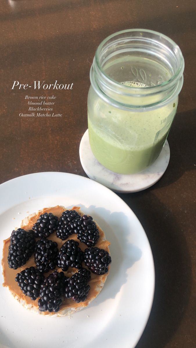 a plate with some blackberries on it next to a jar of green smoothie