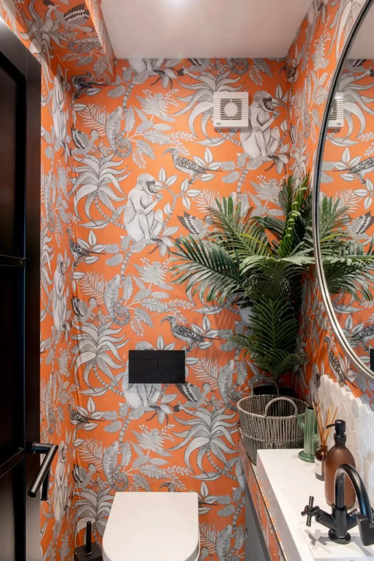 a bathroom with an orange wallpaper and white sink, toilet and mirror in it