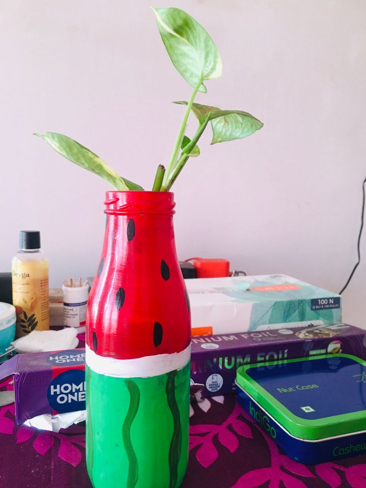 a watermelon painted vase sitting on top of a table next to other items