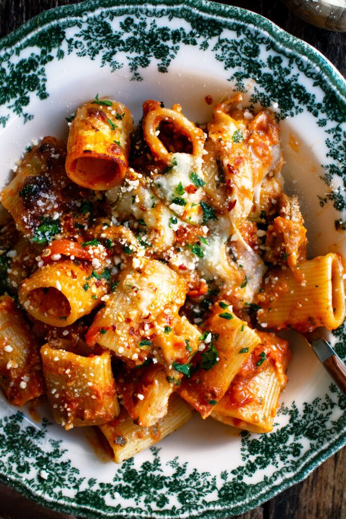 pasta with sauce and parmesan cheese in a white bowl on a wooden table