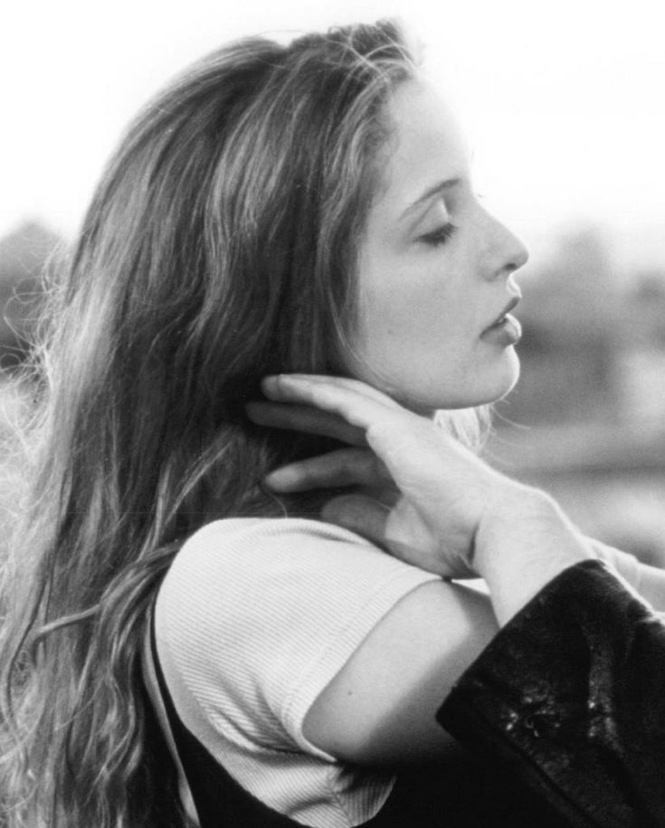 a black and white photo of a woman with her hair blowing in the wind, looking off into the distance