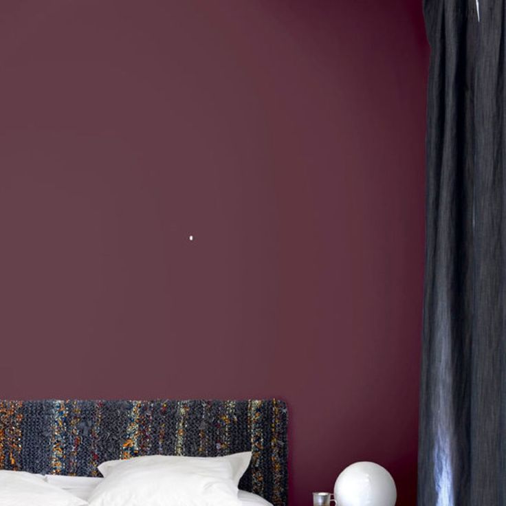 a bed with white pillows and purple walls in a room that has dark red paint on the walls