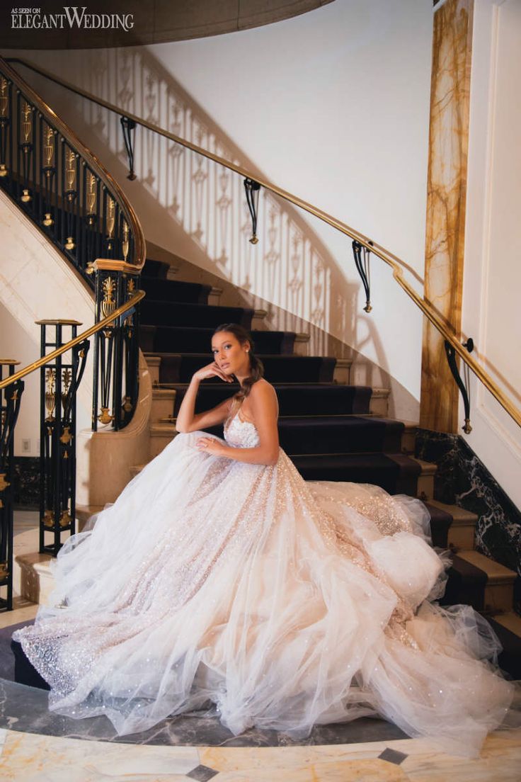 a woman in a wedding dress is sitting on the stairs with her hand under her chin