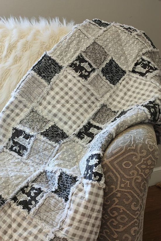 a couch with a blanket on top of it next to a rug and window sill