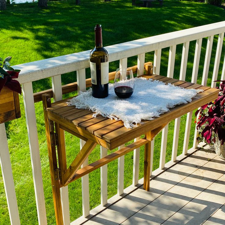 a bottle of wine sitting on top of a wooden table next to a potted plant