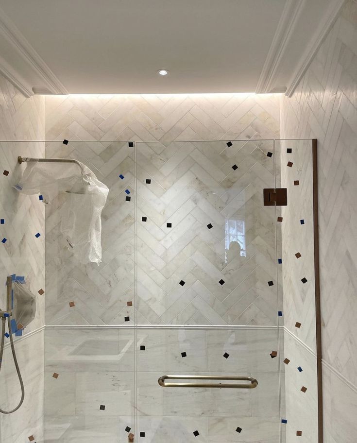 a bathroom with white tile and gold accents on the shower wall, along with a towel rack