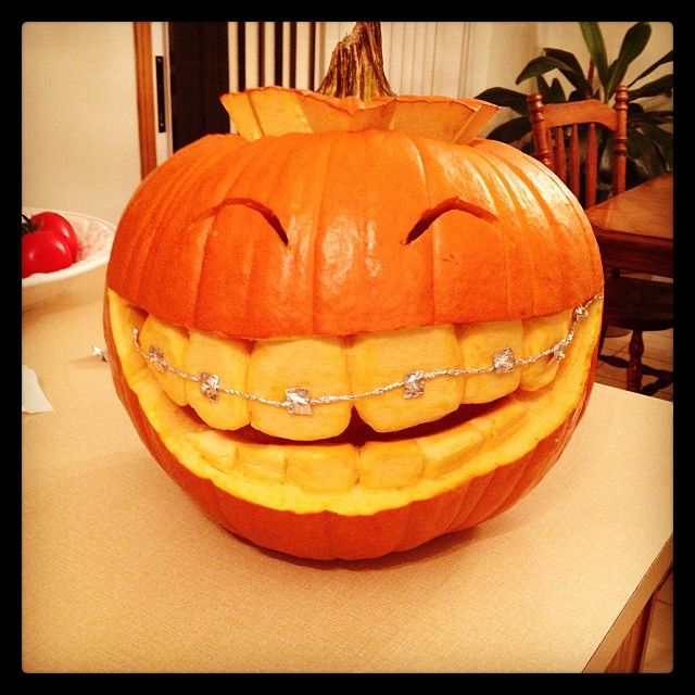 a pumpkin that has been carved to look like a smiling face with teeth and chains on it