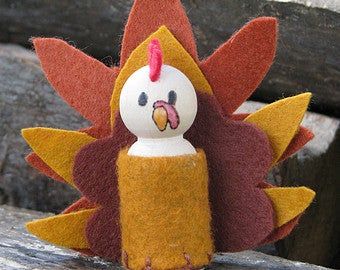 a small stuffed turkey sitting on top of a wooden table next to a piece of wood